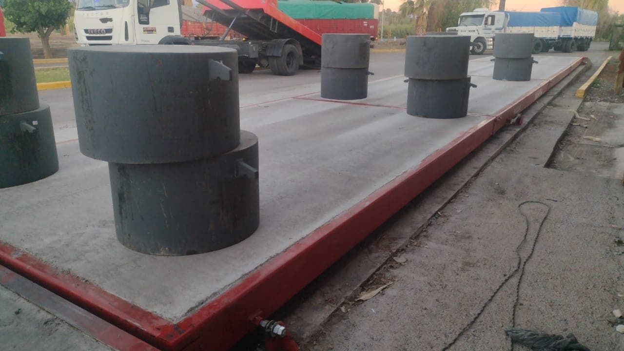 Pesas patrón distribuidas sobre la plataforma de una báscula camionera durante la calibración
